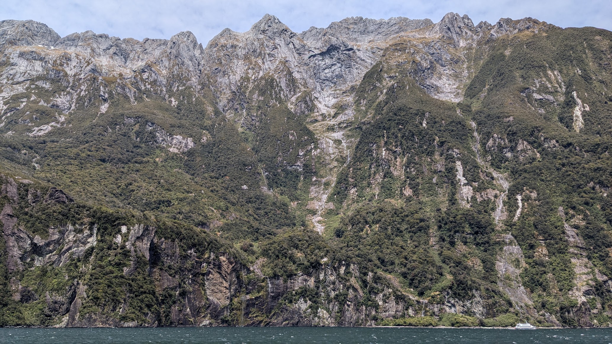 A photo I took of some of the mountains surrounding Milford Sound, featuring one of the touring ships in the foreground for scale