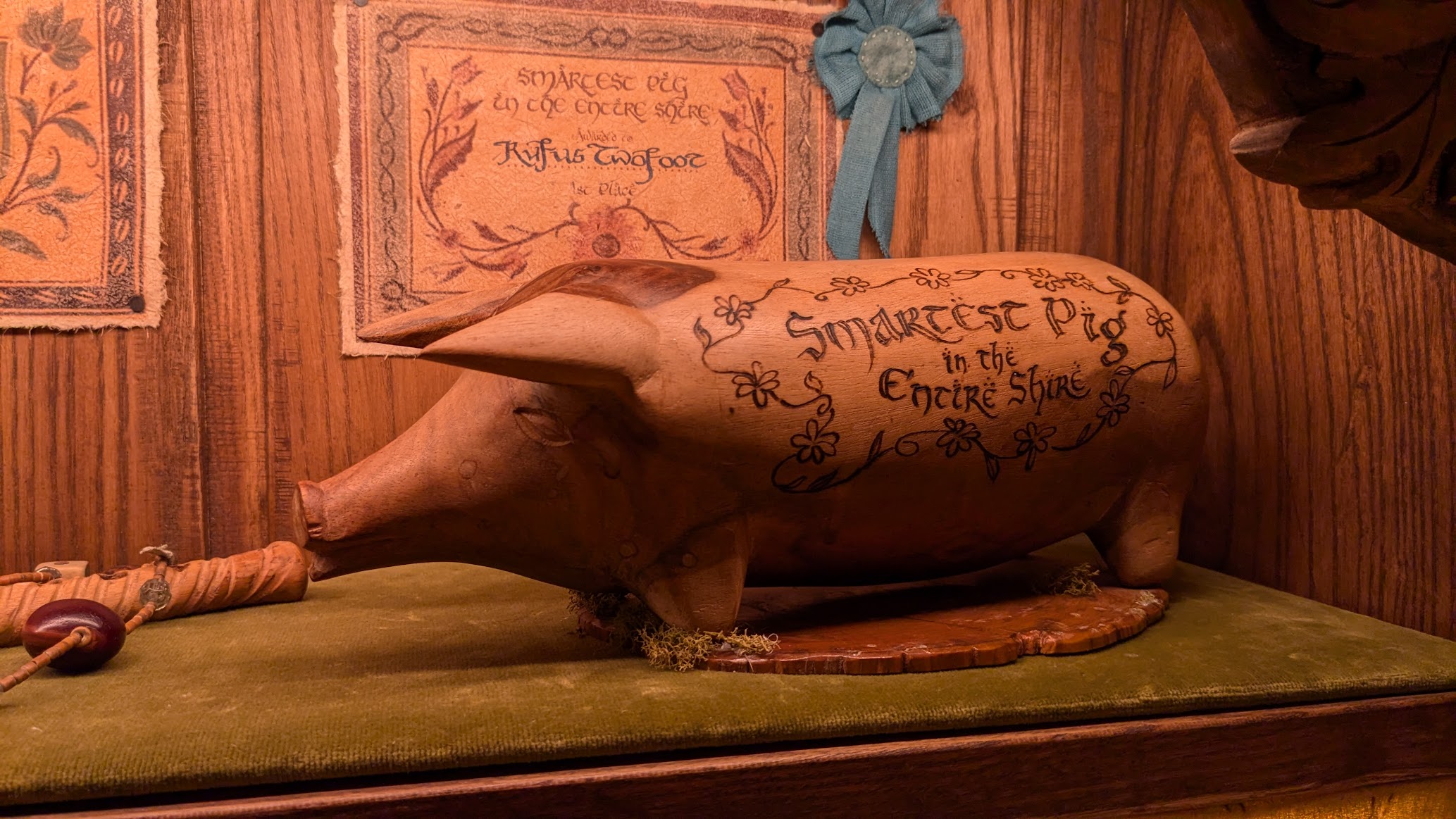 A photo I took from the interior of a Hobbit hole of a small wooden pig on a shelf that had "Smartest Pig in the Entire Shire" written on the side of it in styled script