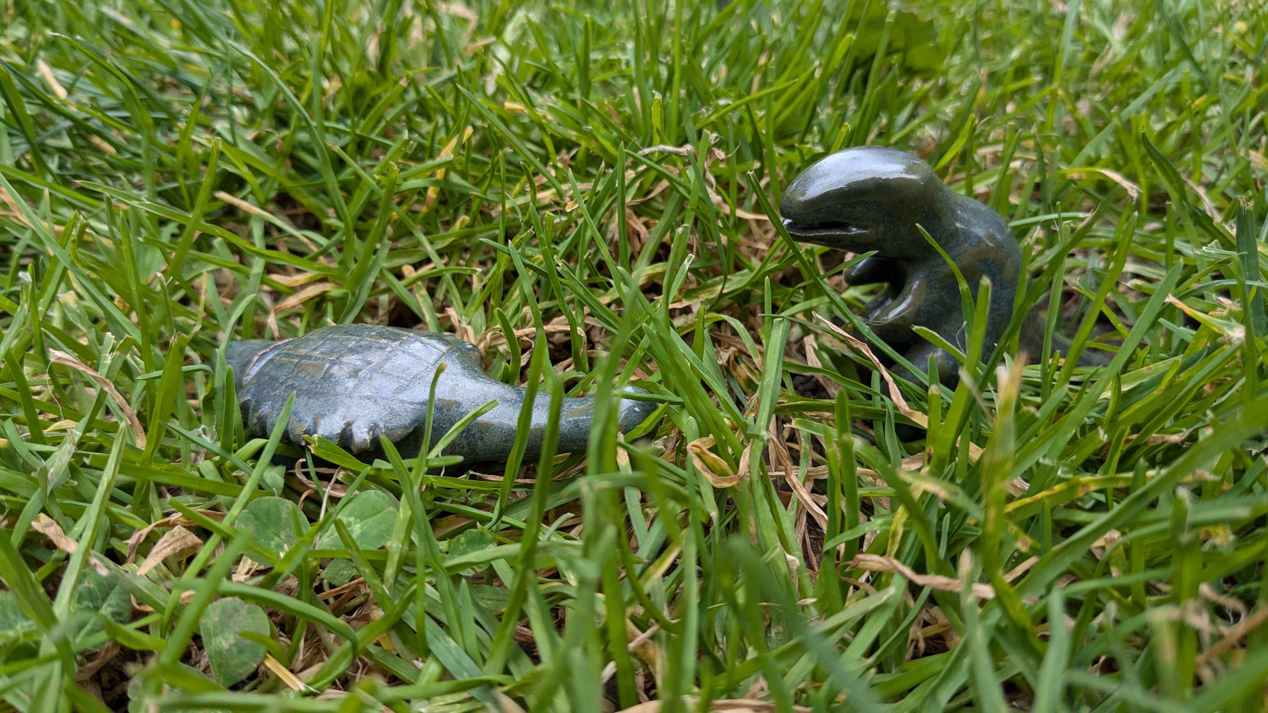 A low-angle shot in the grass of a green ankylosaurus in front of a green tyrannosaurus