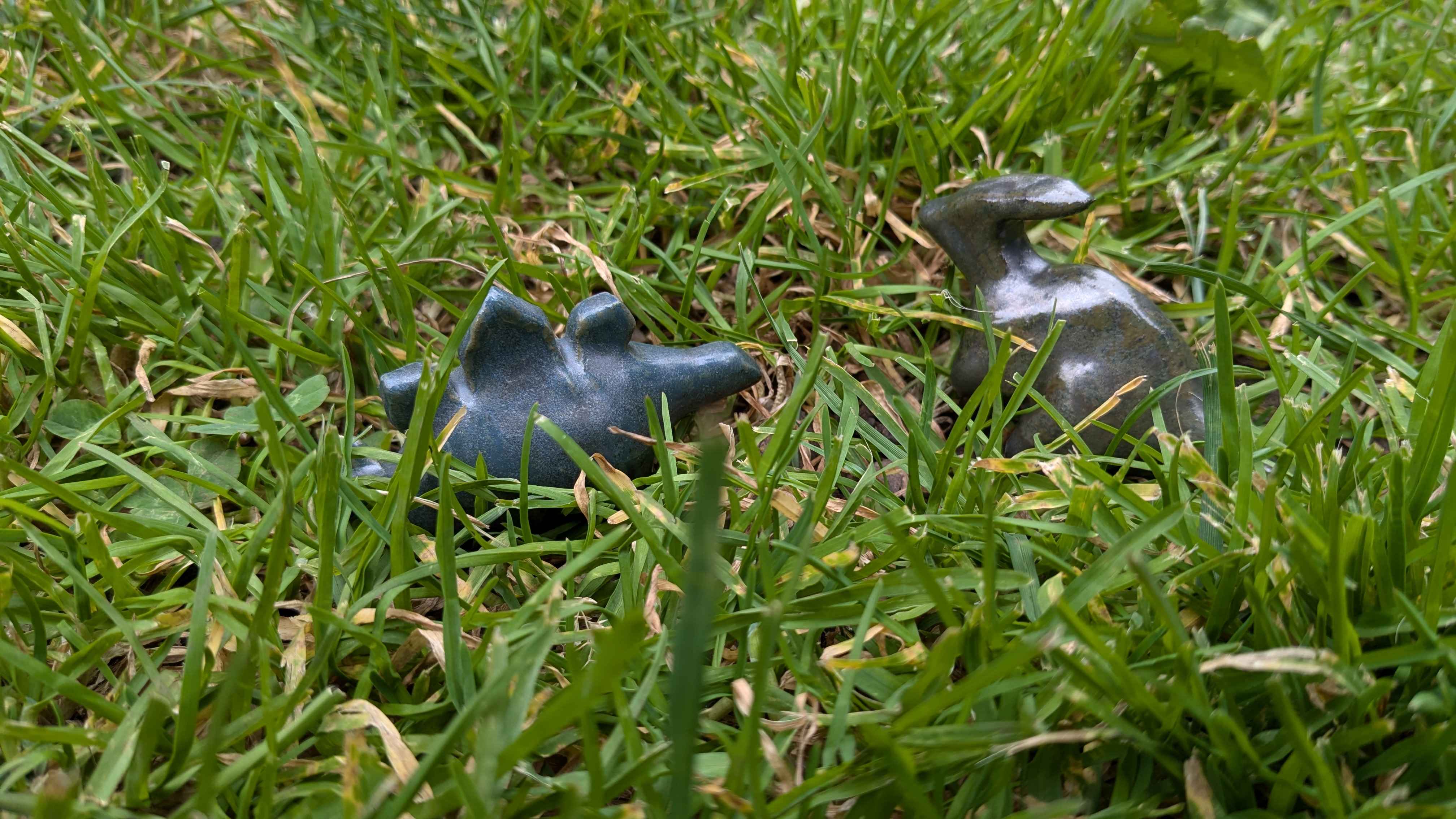 A low-angle shot in the grass of a blue-gray stegosaurus with the new method of cutting out dorsal plates on the left and a dark-green parasaurolophus on the right